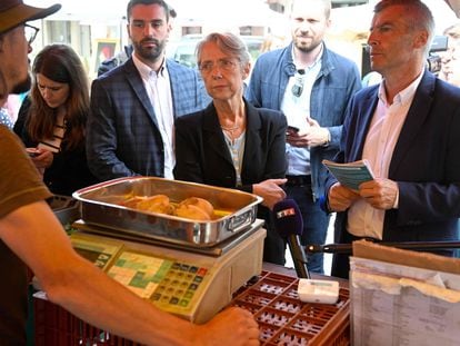 La primera ministra francesa, Élisabeth Borne, escucha este jueves a un vendedor del mercado de Lamballe durante su gira electoral.