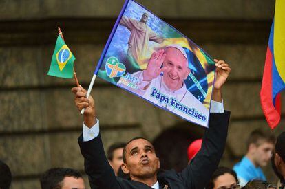 Un joven ondea una bandera brasile&ntilde;a y otra con la foto del Papa esperando la llegada del Sumo Pont&iacute;fice. 