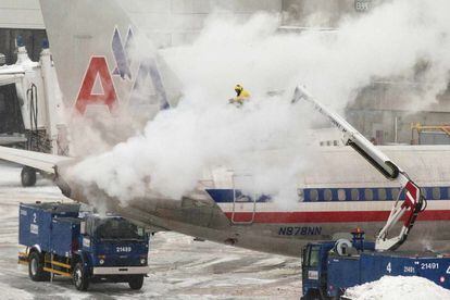 Un trabajador retira la nieve de un avión en Boston.