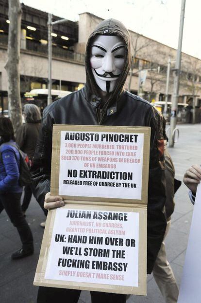 Un manifestantes con m&aacute;scaras del colectivo hacker Anonymous,  sujeta una pancarta de apoyo al fundador de Wikileaks, Julian Assange.  