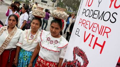 Tres mujeres junto a un cartel con la frase "Tú y yo podemos prevenir el VIH", durante el Día Mundial del sida, en Lima (Perú).