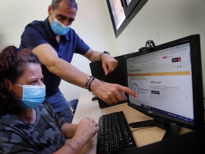 Un hombre ayuda a una mujer a realizar unos trámites 'online'.