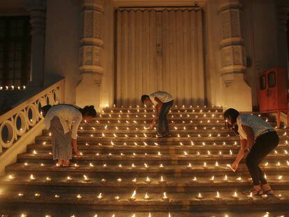 Varias personas encienden velas en la puerta de una iglesia de Colombo en recuerdo de los recientes atentados terroristas en Sri Lanka.