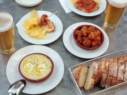 Una mesa de terraza, con una cazuela de atascaburras, albóndigas caseras y cervezas.