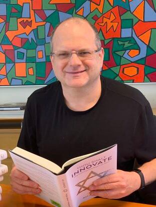 Schwed, in his characteristic black T-shirt, reviews a copy of the book 'Thou Shalt Innovate', dedicated to innovation in Israel and in which Check Point is discussed.