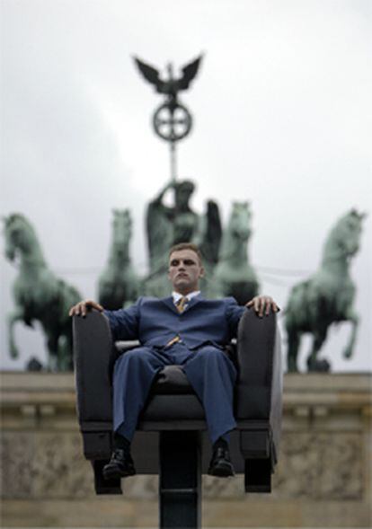 Hombre en un sillón colgado delante de la puerta de Brandeburgo.