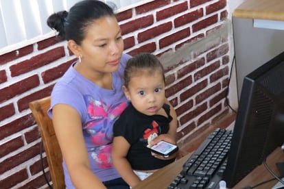 Una mujer trabaja con su hija en el regazo.