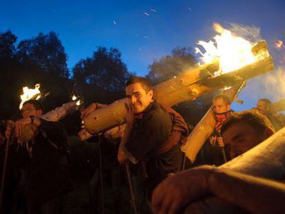 Faillares portando los troncos en llamas desde la monta&ntilde;a hasta la aldea de Isil en Lleida.