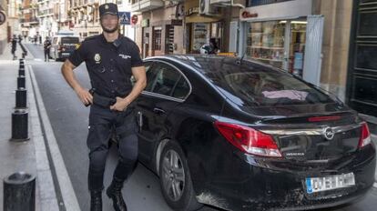 Un membre de la Policia Nacional custodia el vehicle que trasllada dos dels sis policies detinguts a Cartagena.