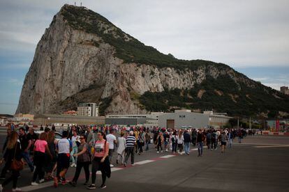 Peatones cruzan la pista en el aeropuerto de Gibraltar, con el peñón al fondo.