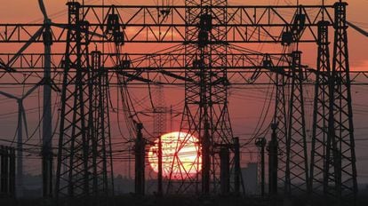 Puesta de sol junto a un tendido eléctrico y unos molinos de viento (izq).