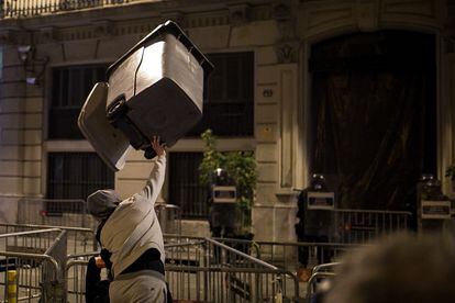 Un joven lanza un contenedor contra agentes antidisturbios de los Mossos este domingo en Barcelona.