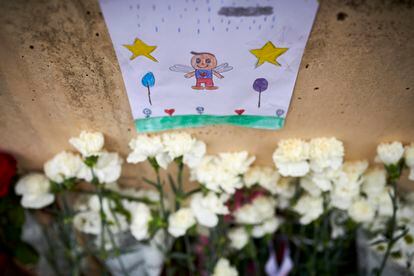 Un dibujo y flores depositados junto al portal donde fue encontrado el menor asesinado en Lardero.