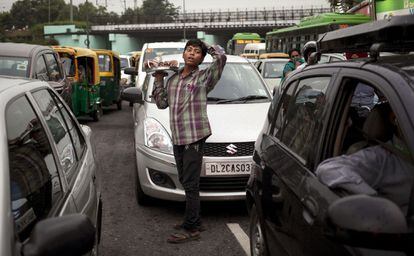 Un nen ven cocos entre els cotxes a Nova Delhi (Índia).