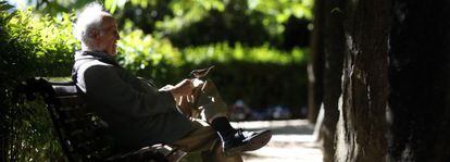Un hombre juega con un pájaro en el parque del Retiro de Madrid.
