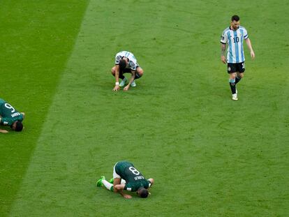 Leo Messi deja el campo mientras algunos jugadores saudíes rezan al término del partido.