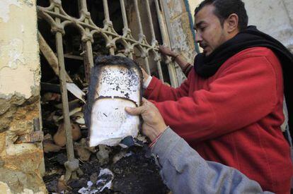 Un hombre saca un manuscrito quemado del Instituto Egipcio.
