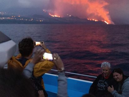 Dos turistas fotografían el volcán, al fondo, desde el barco Fancy.