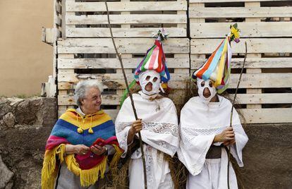 Una mujer posa con un par de jóvenes vestidos de 'Zarramaches', personaje del carnaval tradicional de Casavieja, en Ávila, durante una reunión de máscaras y personajes carnavalescos.
