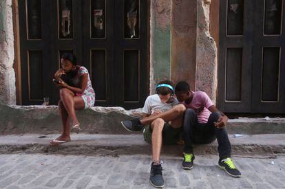 Tres j&oacute;venes utilizan sus tel&eacute;fonos m&oacute;viles para conectarse a Internet en La Habana.