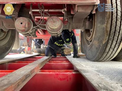 An agent from the Secretariat of Citizen Security of Mexico City retrieves packets of cocaine from the bottom of the truck.