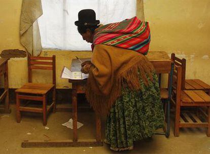Una indígena boliviana marca la papeleta de votación del referéndum constitucional en un colegio electoral en El Alto (La paz)