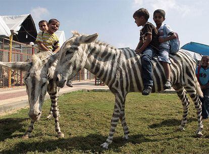 Niños palestinos montan en las falsas cebras el zoo Marah Land en la ciudad de Gaza.