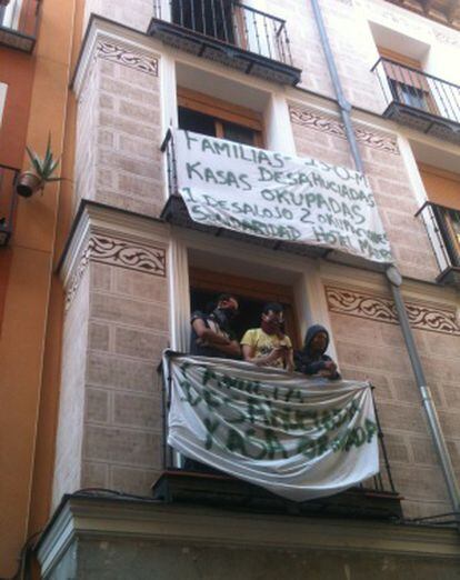 Varios de los okupas del edificio de la calle Tres Peces en uno de los balcones, donde han colocado carteles.