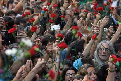 Un grupo de manifestantes levantan claveles durante una protesta multitudinaria frente a la consellería de Economía de Barcelona tras los registros y detenciones que ha realizado la Guardia Civil en varias sedes del Govern.