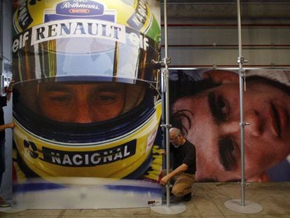 Operarios cuelgan fotos del brasileño Ayrton Senna en una exposición conmemorativa en la pista de carreras de Imola (Italia) en 2014.