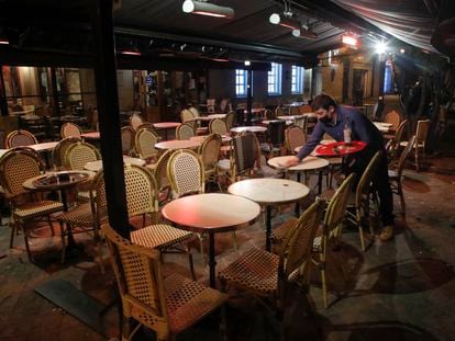 Un camarero termina de limpiar las mesas de un restaurante en Saint Germain-en-Laye, en París, antes de empezar el toque de queda por la pandemia en la noche del viernes.