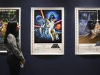 Una empleada de Sothebys observa unos carteles originales de las primeras películas de Star Wars que pondrá a subasta.