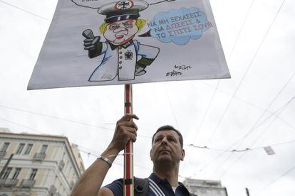 Un manifestante marcha en Atenas mientras sujeta una pancarta con un dibujo de la canciller alemana Angela Merkel vestida como un nazi, durante la huelga general de 24 horas convocada en Grecia.