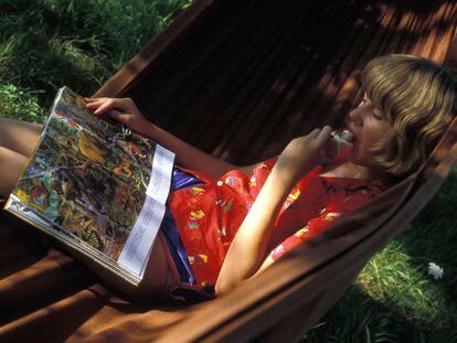 Una niña leyendo un libro de animales en una hamaca.