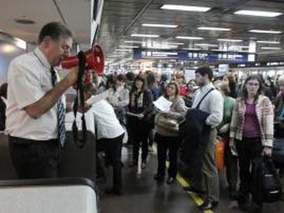 En la imagen, un trabajador de Aerolíneas Argentinas habla a través de un megáfono a los viajeros que se ven afectados por el retraso de los vuelos. EFE/Archivo