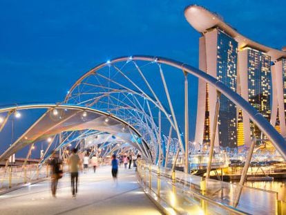 Paseantes en el puente Helix, en Singapur, con el famoso hotel Marina Bay Sands al fondo.