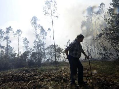 Un hombre camina cerca de las llamas en su finca en A Capela.