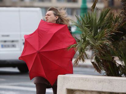 Una mujer se protege del viento en San Sebasti&aacute;n.