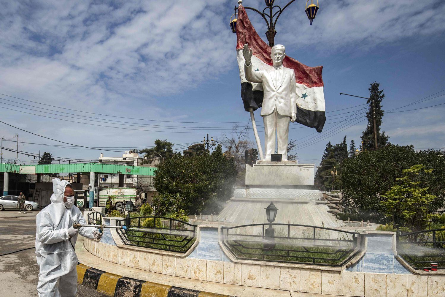 Un trabajador desinfecta una estatua del expresidente sirio Hafez el Asad, en la ciudad de Qamishli, en el nordeste de Siria, el pasado martes.
