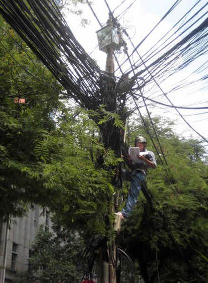 Un operario resolviendo una avería del tendido eléctrico en la antigua Saigón, Vietnam