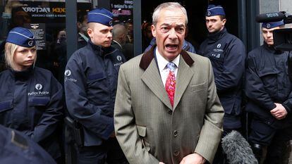 El político británico Nigel Farage habla con los medios de comunicación en la puerta del lugar donde se celebra la conferencia National Conservatism con la policía detrás, el 16 de abril en Bruselas.