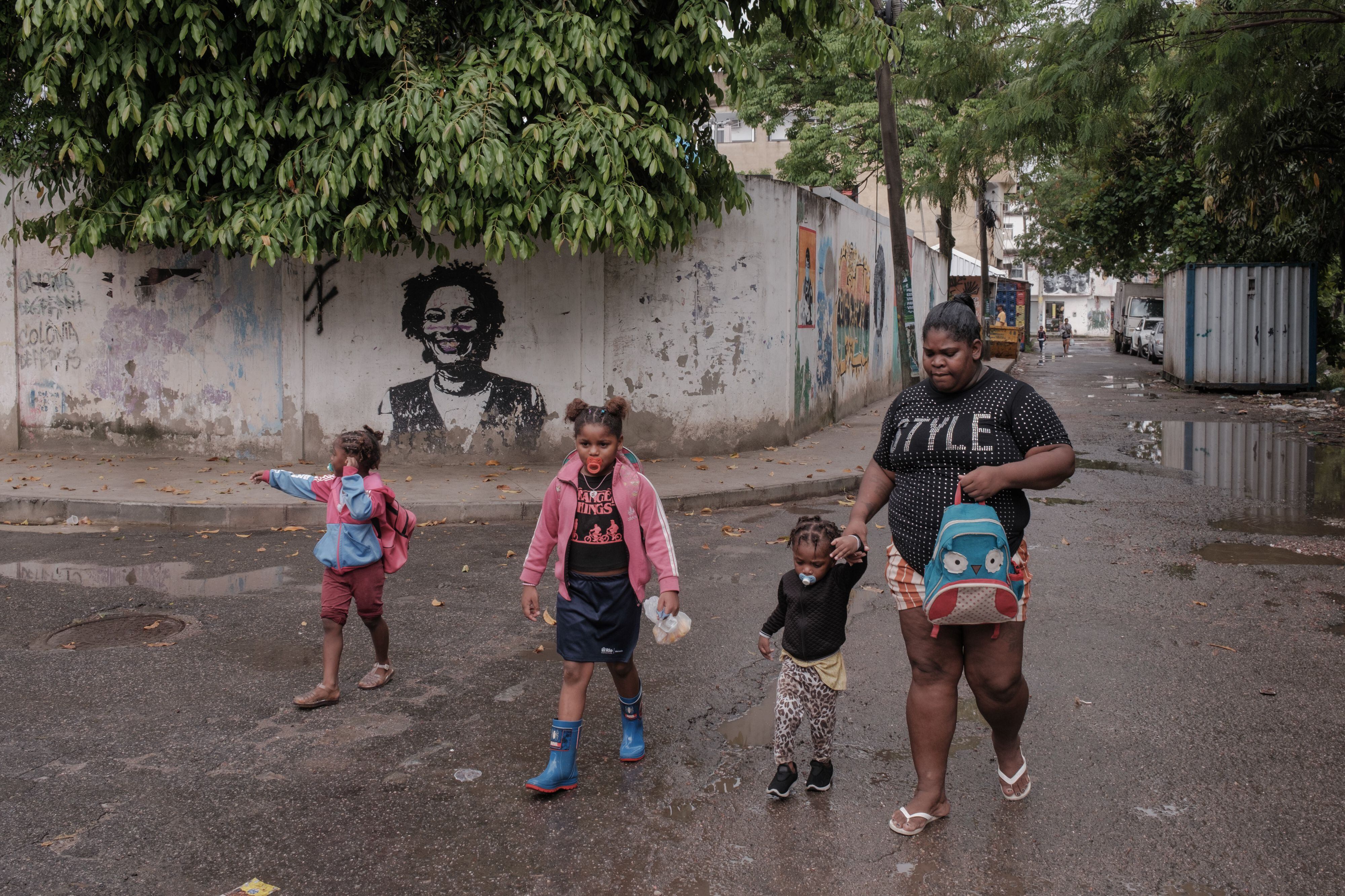 Una mujer y varios niños caminan frente a un mural de Marielle Franco en Río de Janeiro.