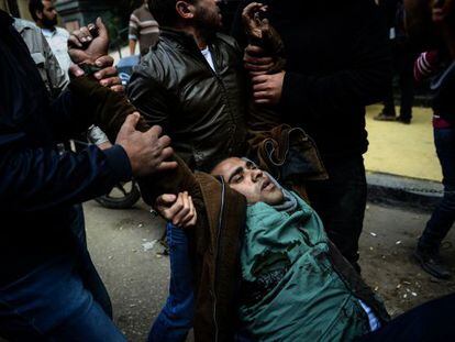 Dos manifestantes opositores evacuan a un herido en El Cairo este s&aacute;bado.