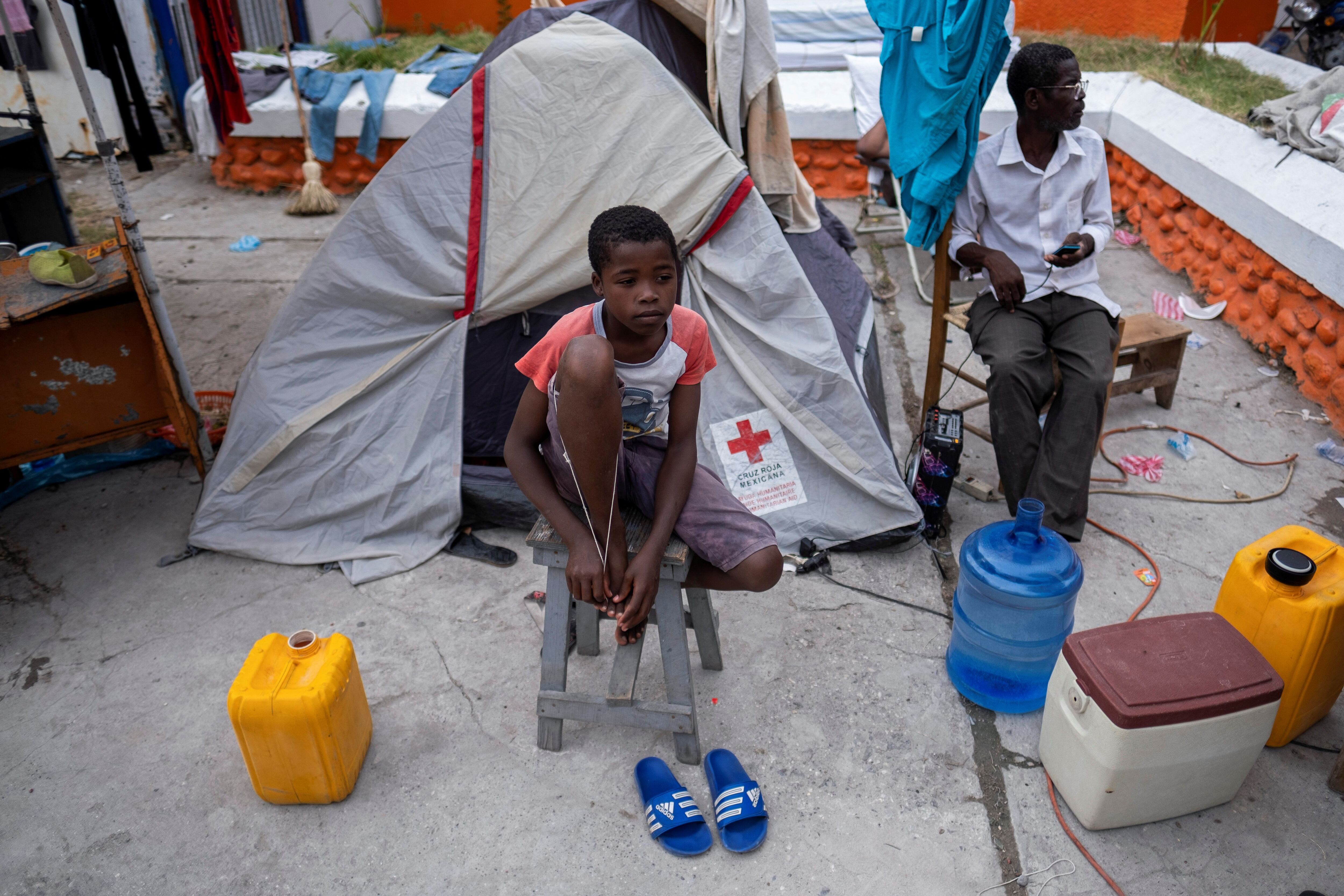 Un niño sentado frente a una carpa de la Cruz Roja, la que es su casa improvisada.