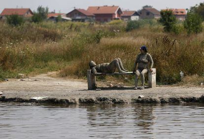 Personas cubiertas de barro medicinal toman el sol junto a una pequeña piscina de aguas minerales en Ovca, Belgrado, Serbia.