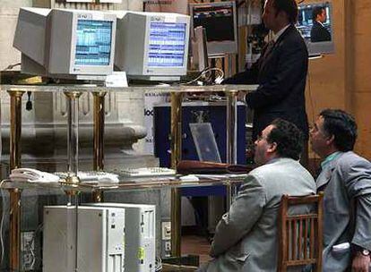 Dos inversores observan pantallas con las cotizaciones en el patio de operaciones de la Bolsa de Madrid.