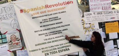 Una joven pega un cartel con las reivindicaciones en la Puerta del Sol.