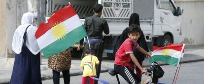 Un niño kurdo monta en una bici decorada con banderas kurdas frente a un centro electoral en Erbil, en la región autónoma del Kurdistán iraquí.