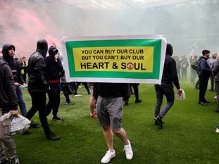 Un aficionado del United, en Old Trafford con una cartel que dice: "Tú puedes comprar nuestro club, pero no nuestro corazón y nuestra alma".