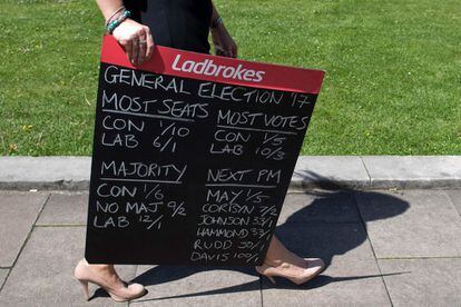 Una mujer sujeta un letrero de una casa de apuestas donde aparecen las probabilidades que tiene cada partido y candidato de ganar las elecciones generales. La imagen ha sido tomada en College Green, Reino Unido, este miércoles.